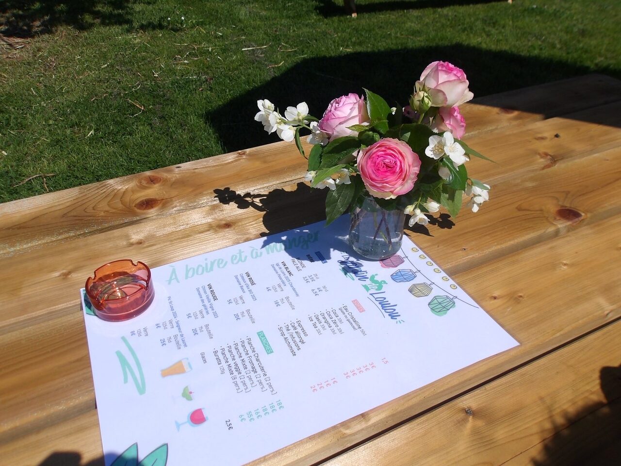 La carte du Jardin de Loulou avec un bouquet de roses sur table en bois