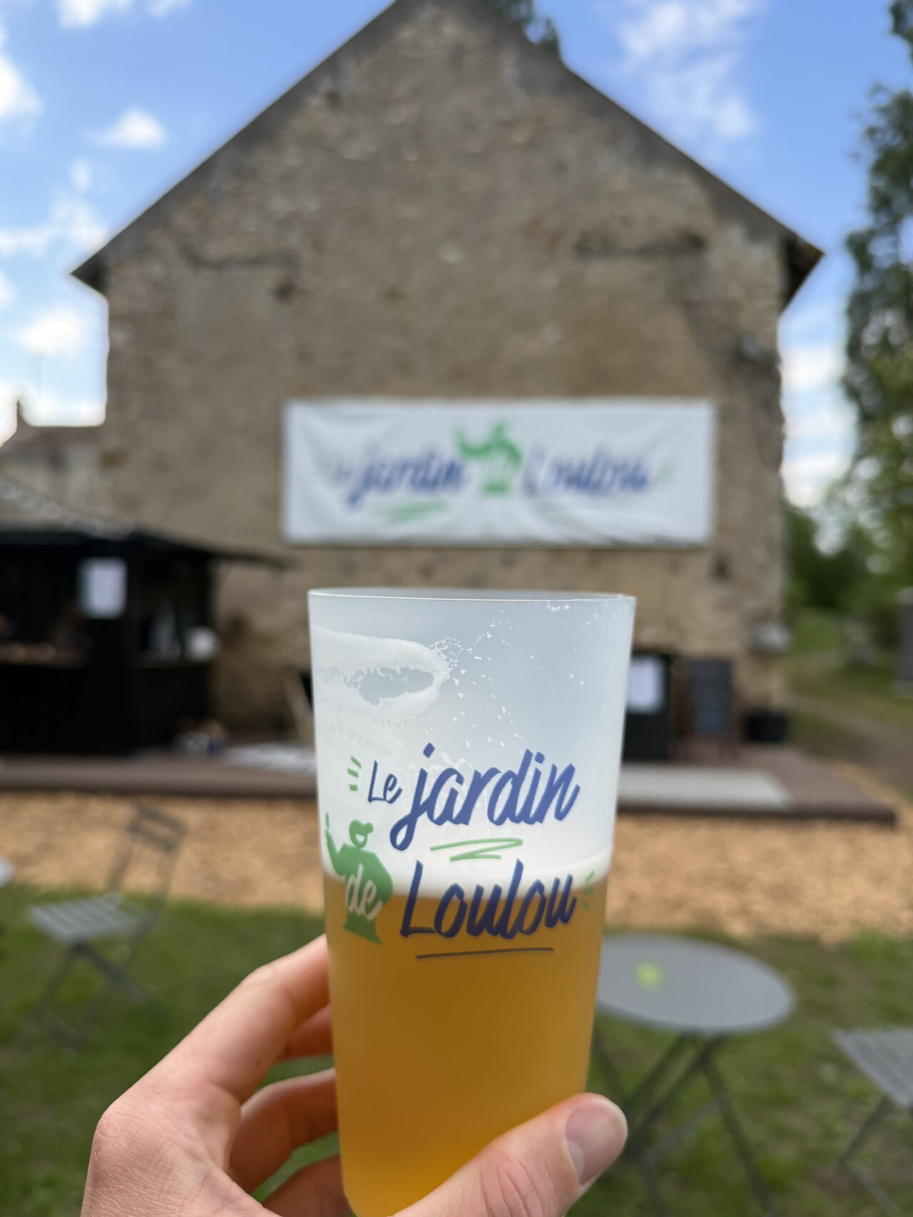 Pinte de bière Le Jardin de Loulou tenue devant la grange en pierre